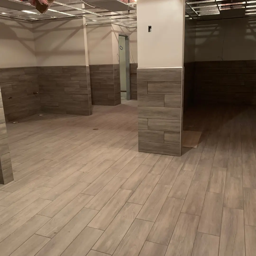 Shaw Floors wood-look porcelain plank tile installed on the floors and lower walls of the in-progress Treatt USA restroom