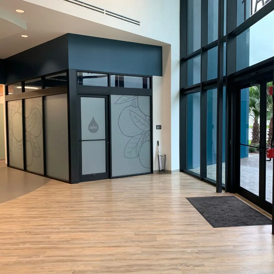 Treatt USA front lobby with light wood-look LVP running into the building entry and the Grove glass conference room